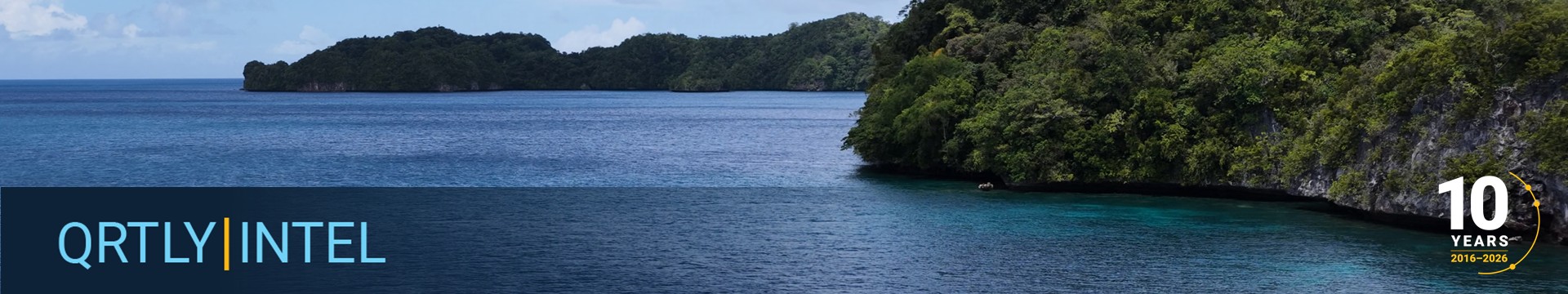 Panoramic view of the ocean meeting the tree filled cliffside.